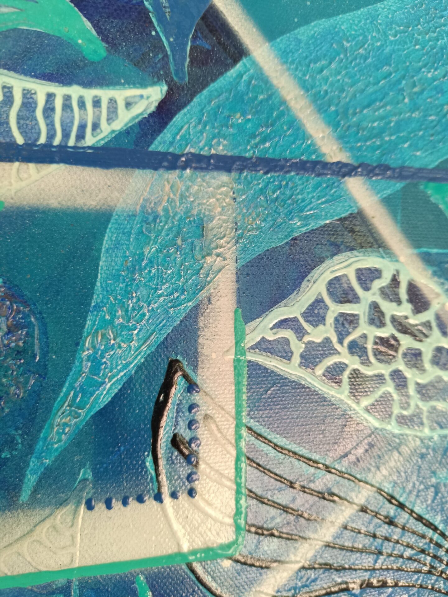 Zoom de précision sur le relief des feuilles stylisées peintes en blanc.